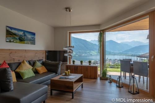 a living room with a couch and a large window at Apartments Adlerhorst Top 1 Zell am See including Zell am See-Kaprun Summercard in Zell am See