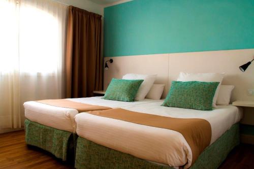 two beds in a hotel room with a green wall at Apartamentos San Marcial in Puerto del Carmen