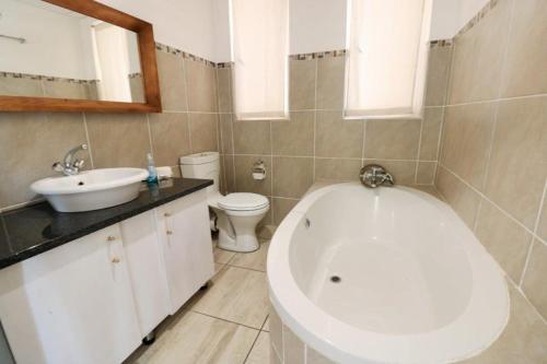 La salle de bains est pourvue d'une baignoire, d'un lavabo et de toilettes. dans l'établissement 17 Umdloti Resort, à Umdloti