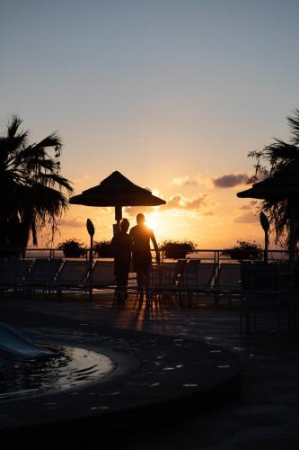 two people standing under an umbrella at the beach at Hotel Villaggio Stromboli in Santa Domenica