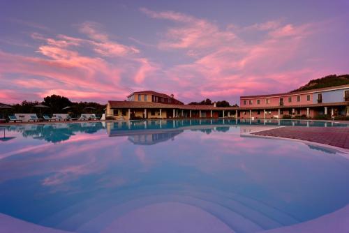 a large swimming pool with a sunset in the background at ECO HOTEL ORLANDO Sardegna in Villagrande Strisaili