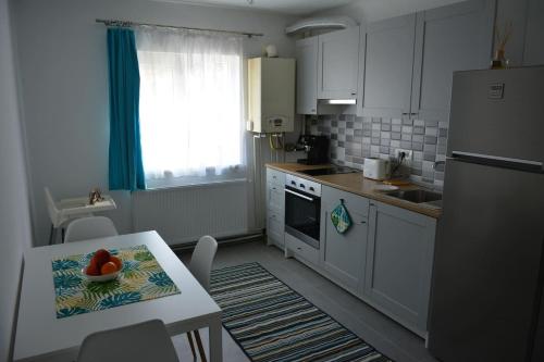 a kitchen with white cabinets and a table with a bowl of fruit at Cosy Home at 100 m from Iulius Town in Timişoara