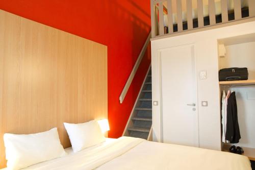 a bedroom with red walls and a bed with white sheets at B&B HOTEL Montpellier 2 in Saint-Jean-de-Védas