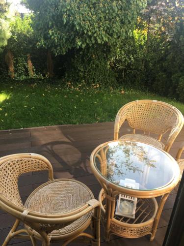 three wicker chairs and a glass table on a patio at Apartament Neptun in Jastrzębia Góra