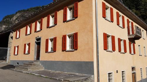 a building with red shutters on the side of it at BnB Ai Cav Calanca in Arvigo