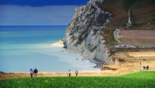 a group of people standing on a beach next to a cliff at Chambre d'hôtes Les Nymphéas in Wimereux