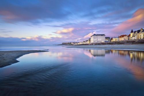 een uitzicht op een strand met gebouwen en het water bij Chambre d'hôtes Les Nymphéas in Wimereux