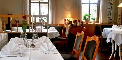 ein Restaurant mit Tischen und Stühlen mit weißem Tischtuch in der Unterkunft Landhotel Gemeindeschänke in Wanfried