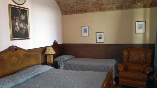 a bedroom with two beds and a chair at Casa Tavasso in Asti