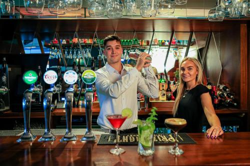 a man and woman standing at a bar with wine glasses at Gleesons Townhouse Booterstown in Dublin
