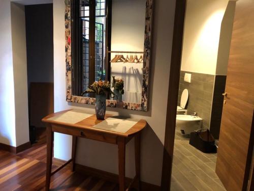 La salle de bains est pourvue d'une table et d'un vase de fleurs. dans l'établissement Suite Michelangelo, à Rome