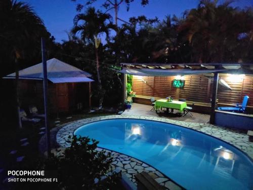 - une piscine avec une terrasse et une table la nuit dans l'établissement Chalet "BIENVENUE NOUT KAZ", à Saint-Gilles-les Hauts
