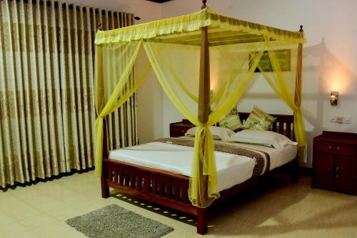 1 dormitorio con cama con dosel y cortinas amarillas en Rainforest Lodge, Deniyaya, en Deniyaya