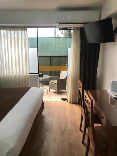 a bedroom with a bed and a desk and a dining room at Faraona Grand Hotel in Lima