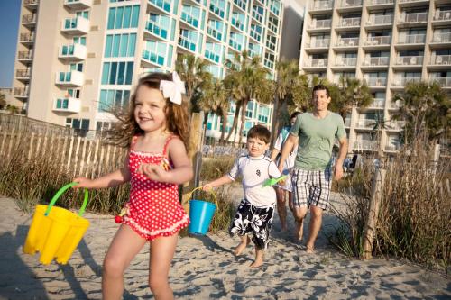 a little girl and boy playing in the sand at the beach at Captain's Quarters Resort in Myrtle Beach