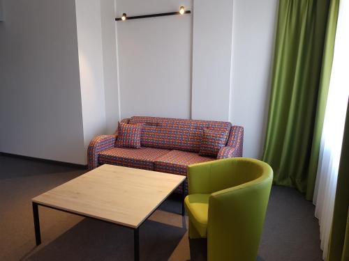 a room with a couch and a table and a chair at A&M Hotel with free parking in Plovdiv