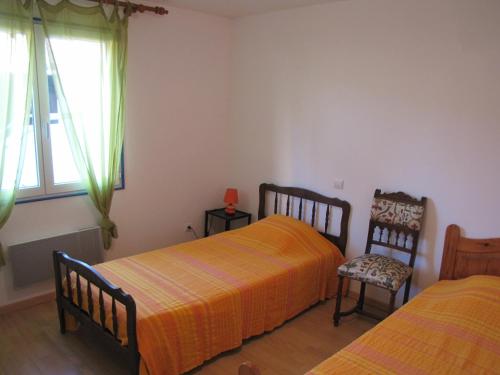 une chambre avec deux lits et une chaise et une fenêtre dans l'établissement maison de village entre mer et montagne, à Roujan