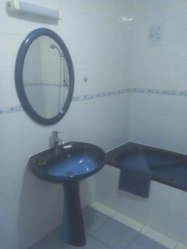 une salle de bain avec un lavabo bleu et un miroir dans l'établissement maison de village entre mer et montagne, à Roujan