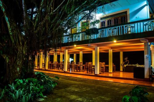 a building with a balcony with tables and chairs at Rainforest Lodge, Deniyaya in Deniyaya