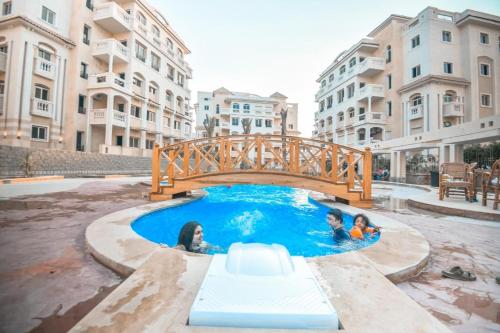 two children swimming in a pool with a bridge at Ramco For Furnished Apartments And Accommodation Compound Leila in Cairo