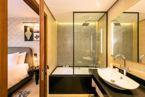 a bathroom with a tub and a sink and a bed at Radisson Blu Hotel Casablanca City Center in Casablanca