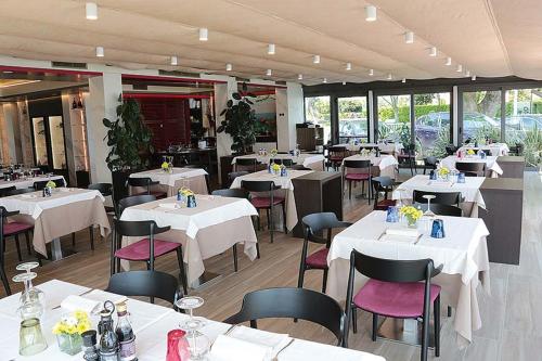 シルミオーネにあるホテル オーロラのテーブルと椅子、白いテーブルと椅子が備わるレストラン
