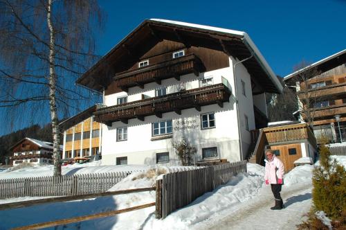 uma mulher parada na neve em frente a uma casa em Gästehaus Obererlacher em Obertilliach