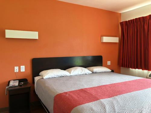 a bedroom with a bed with an orange wall at Motel 6-Clute, TX in Clute