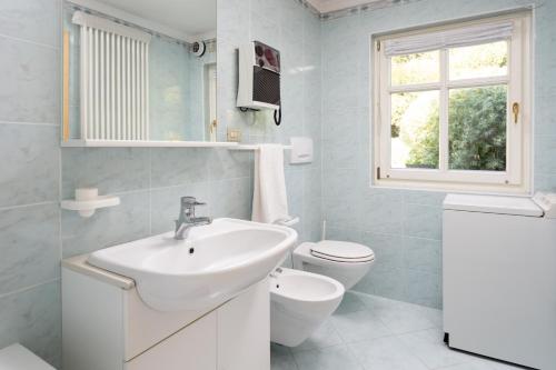 a white bathroom with a sink and a toilet at Kristiania in Campitello