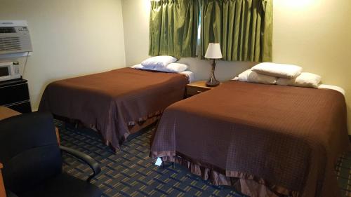 a hotel room with two beds and a chair at Budget Inn Tonawanda in Tonawanda