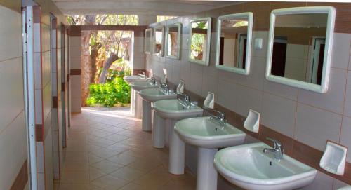 Baño con una fila de lavabos y espejos en Camping Nopigia, en Kissamos