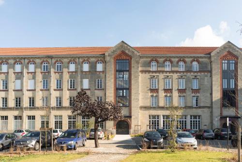 un grand bâtiment avec des voitures garées devant lui dans l'établissement Hotel Saint Louis Beaulieu - Bordeaux, à Bordeaux