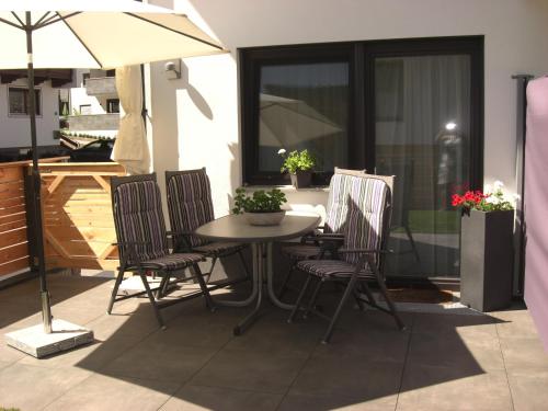 einen Tisch und Stühle auf einer Terrasse mit Sonnenschirm in der Unterkunft die Gartenwohnung - Tanja Tipotsch in Schwendau