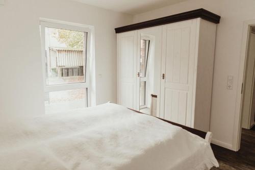 um quarto branco com uma cama e uma janela em Apartment Strandläufer em Aurich