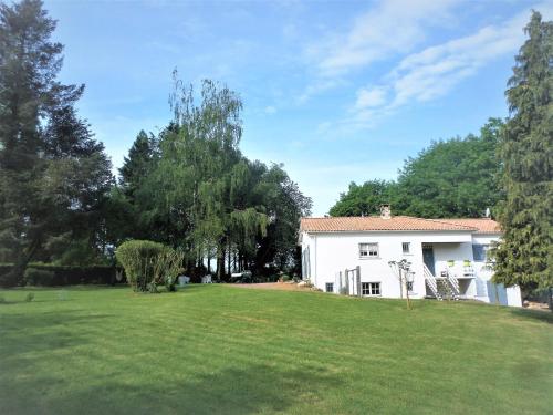 a white house with a large green yard at La Folie in Breuil-Barret