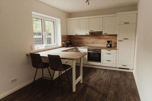 uma cozinha com armários brancos e uma mesa e cadeiras de madeira em Apartment Strandläufer em Aurich