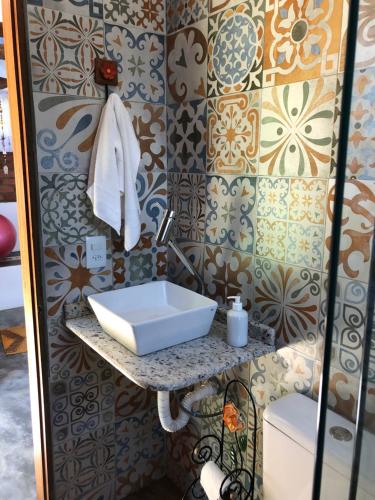 La salle de bains est pourvue d'un lavabo blanc sur un mur. dans l'établissement Sítio Mutandis, à Itamonte