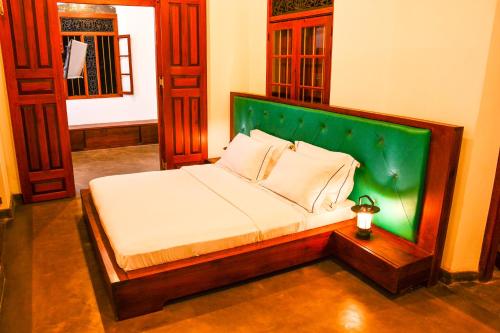 um quarto com uma cama com uma cabeceira verde em Rookada Heritage em Ambalangoda