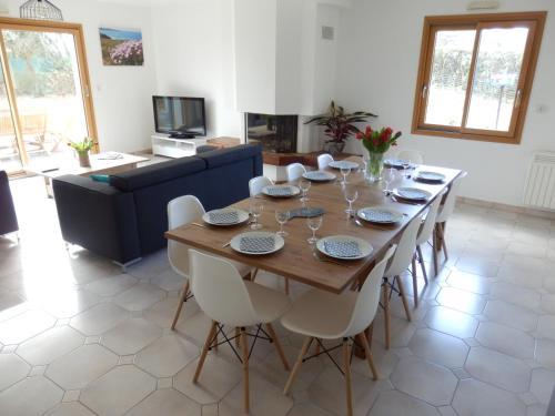 une salle à manger avec une table en bois et des chaises blanches dans l'établissement Villa à la croisée des baies, à Tréméoc