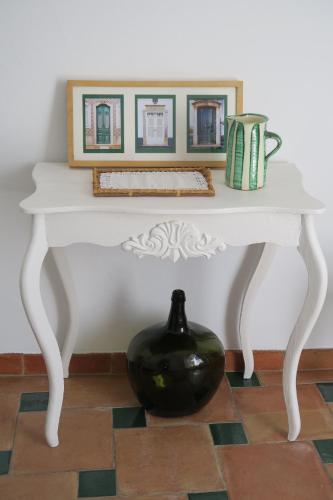 a white table with a black vase on the floor at Azul Sul in Tavira