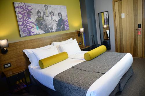 a bedroom with a large bed with white sheets and yellow pillows at Royal Court Hotel in Ramallah