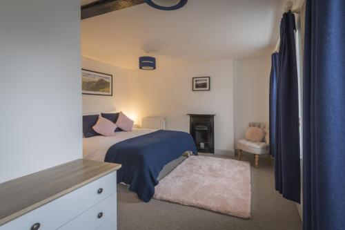 a bedroom with a bed with a blue blanket and a chair at Finest Retreats - Tegannedd - Luxury Grade II Listed Cottage With Hot Tub in Ffestiniog