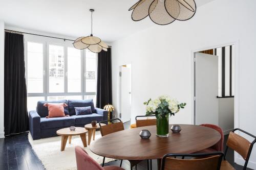 Una sala de estar con una mesa y un sofá azul. en Habitat Parisien - Ponthieu Champs Elysées, en París
