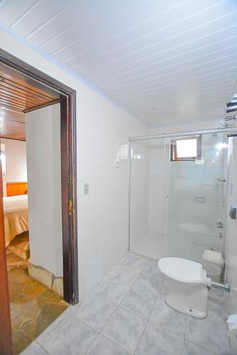 a bathroom with a toilet and a glass shower at Hotel Cabeça de Boi in Monte Verde