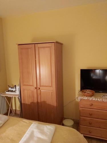 1 dormitorio con un gran armario de madera y TV en Portrush/ballyhome en Portrush