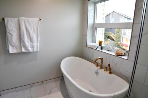 baño con bañera blanca y ventana en Aurora Guest house, en Yellowknife