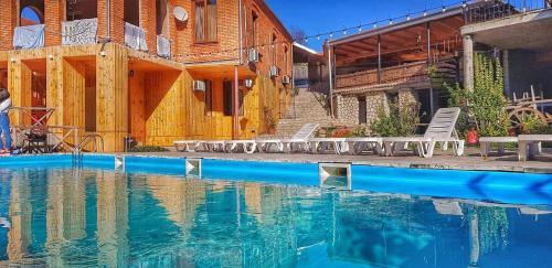 a swimming pool with chairs next to a building at Guest House Marani in Sighnaghi