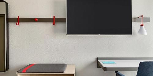 a room with a desk and a tv on a wall at avid hotel Augusta W - Grovetown by IHG in Grovetown
