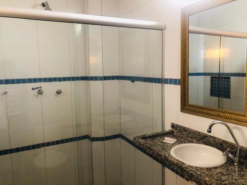 a bathroom with a shower with a sink and a mirror at Hotel Orla Guest House in Petrolina