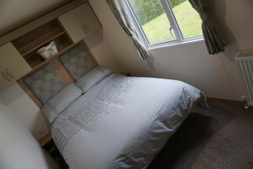 a bedroom with a white bed with a window at MPoint36 at Tattershall Lakes Hot Tub Lake Views 3 Bedrooms in Tattershall